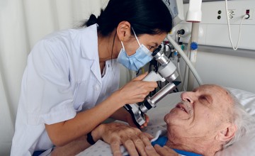 Une médecin ausculte les yeux d'un patient au CHUV