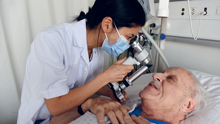 Une médecin ausculte les yeux d'un patient au CHUV