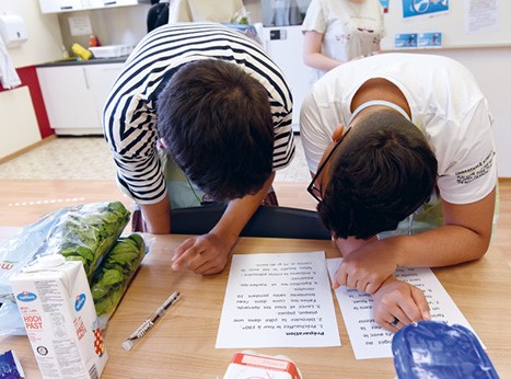 Deux élèves sont penchés sur une feuille de recettes