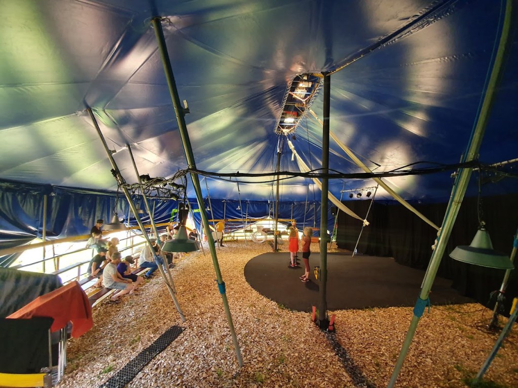 Vue de l'intérieur d'un chapiteau de cirque avec des enfants assis et d'autres sur la scène