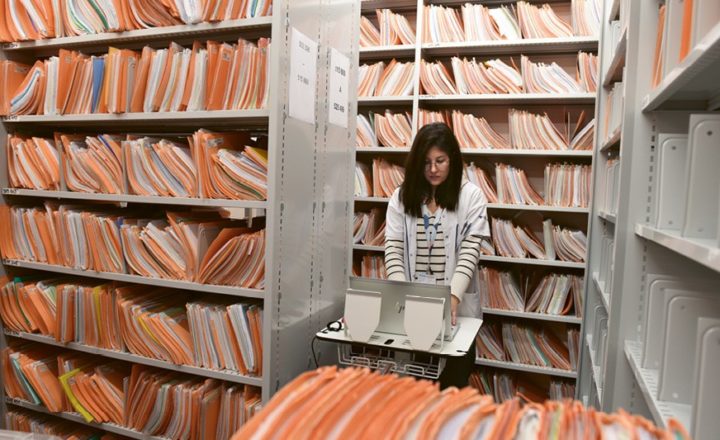 Photo d'une collaboratrice dans les archives de l'Hôpital, contenant les dossiers des patients.