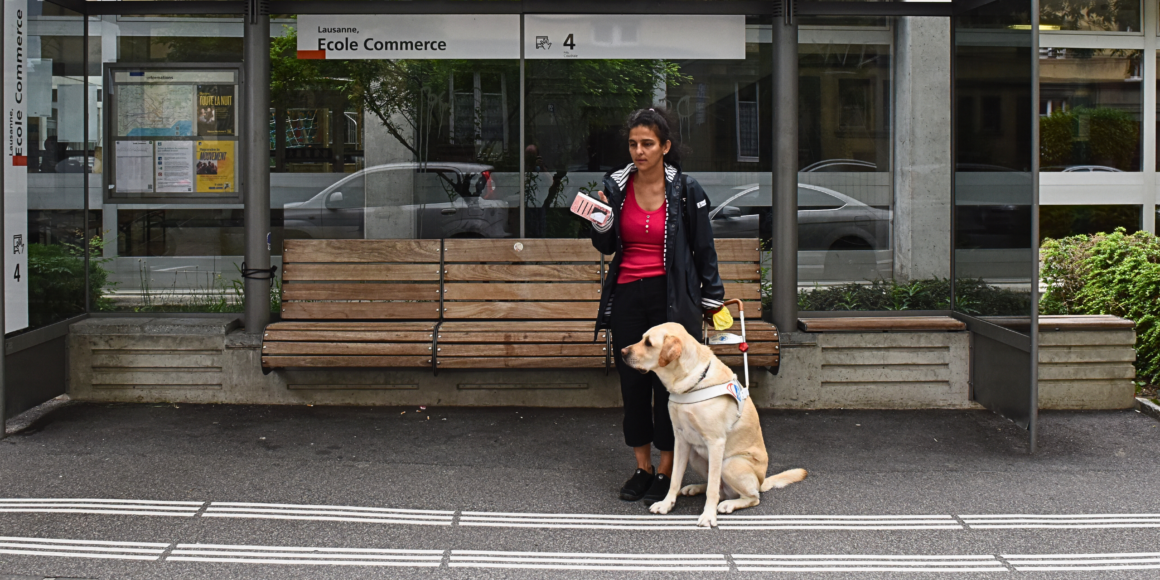 Rania, malvoyante, attendant à un arrêt de bus avec son chien guide