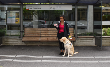 Rania, malvoyante, attendant à un arrêt de bus avec son chien guide