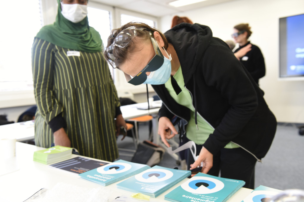 Une participante à la formation en déficience visuelle essaie de lire en portant des lunettes qui simulent une forte réduction du champ visuel.