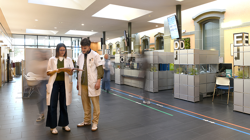 Une médecin et un collaborateur des admissions en train de discuter du dossier d'un patient dans la salle d'attente de la policlinique.